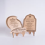 Two wooden Qurban certificates on a stand with engraved text on a white background
