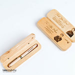 A personalized wooden pen with gold accents, engraved with a name, placed in an open wooden box with a lid, on a white background.