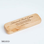A personalized wooden pen with gold accents, engraved with a name, placed in an open wooden box with a lid, on a white background.
