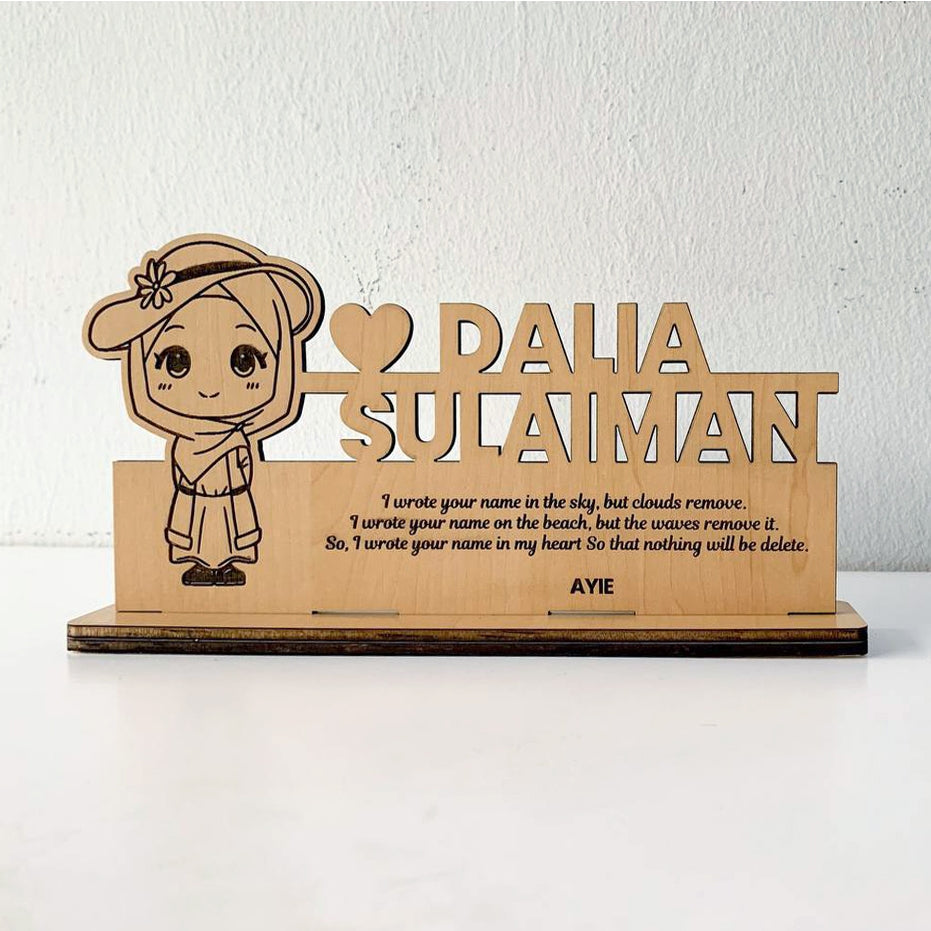 A custom wooden table stand signage with an engraved portrait and text, displayed on a desk.