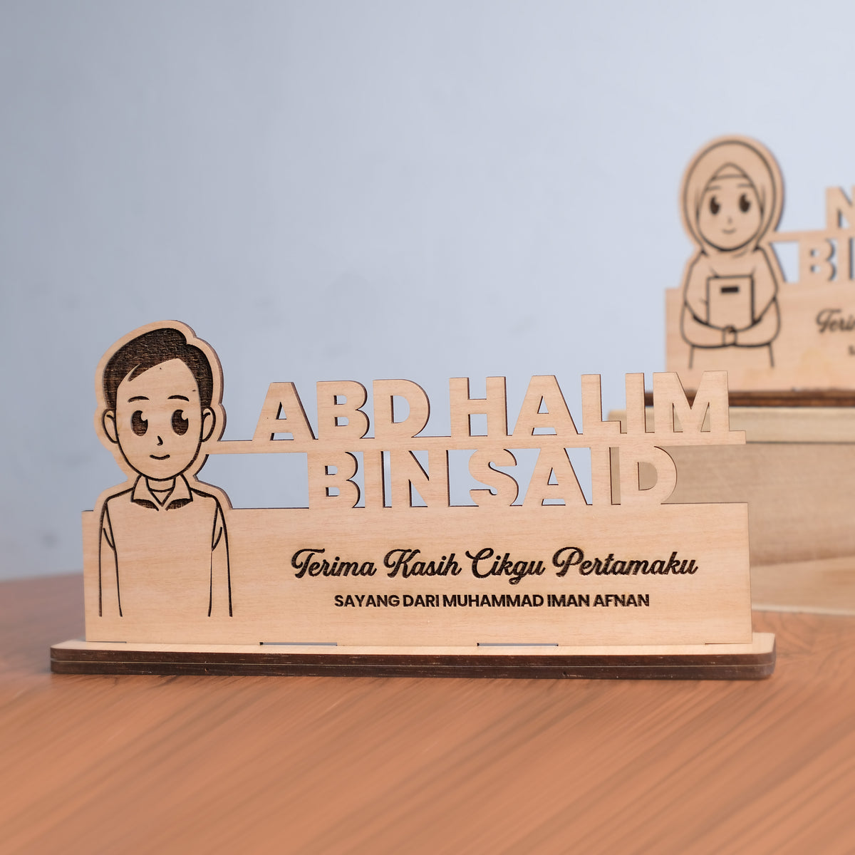 Wooden plaque with a cartoon character and engraved text on a wooden stand.
