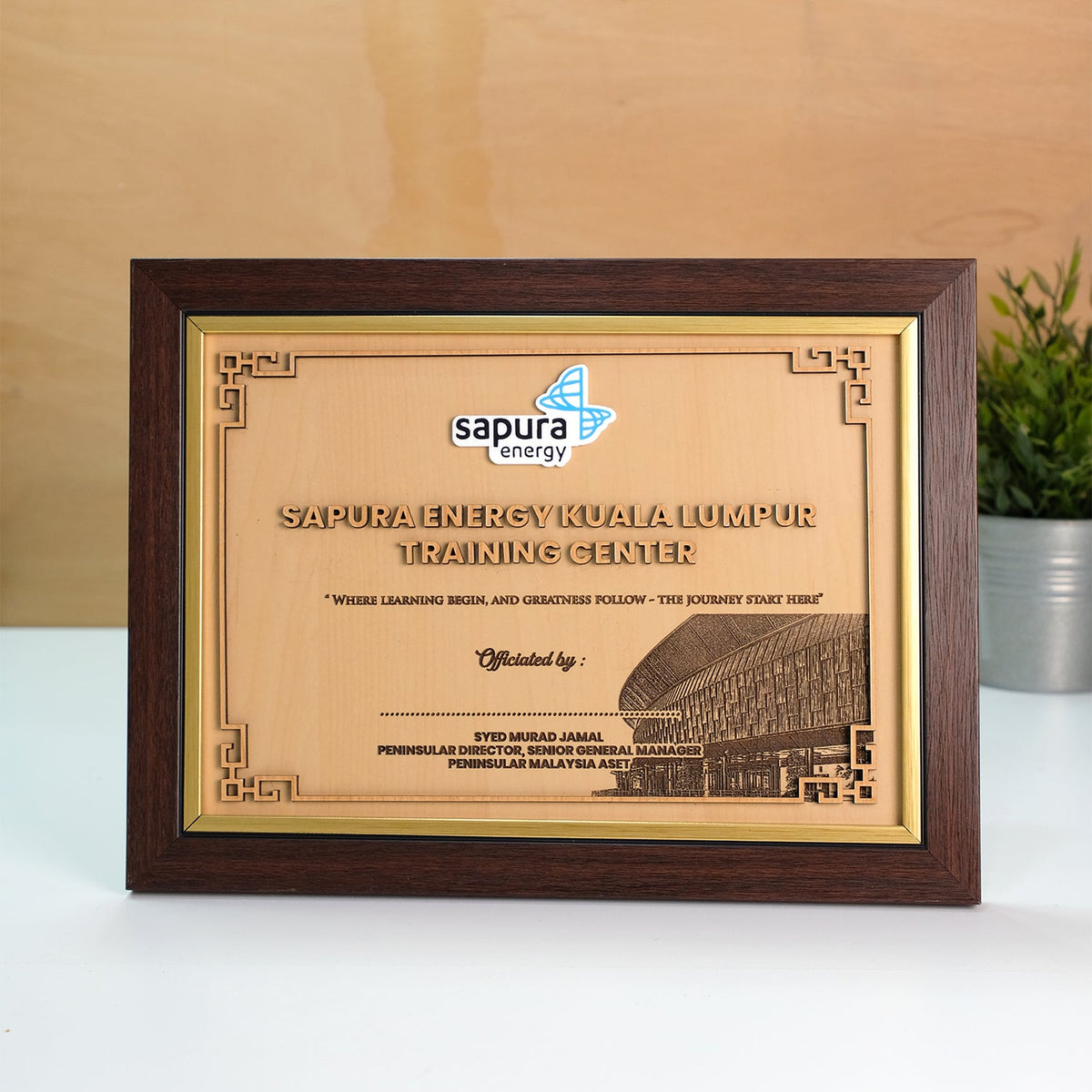 Framed certificate with 'Sapura Energy' logo on a wooden surface.