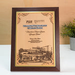 Framed academic award or certificate on a white surface with a plant in the background