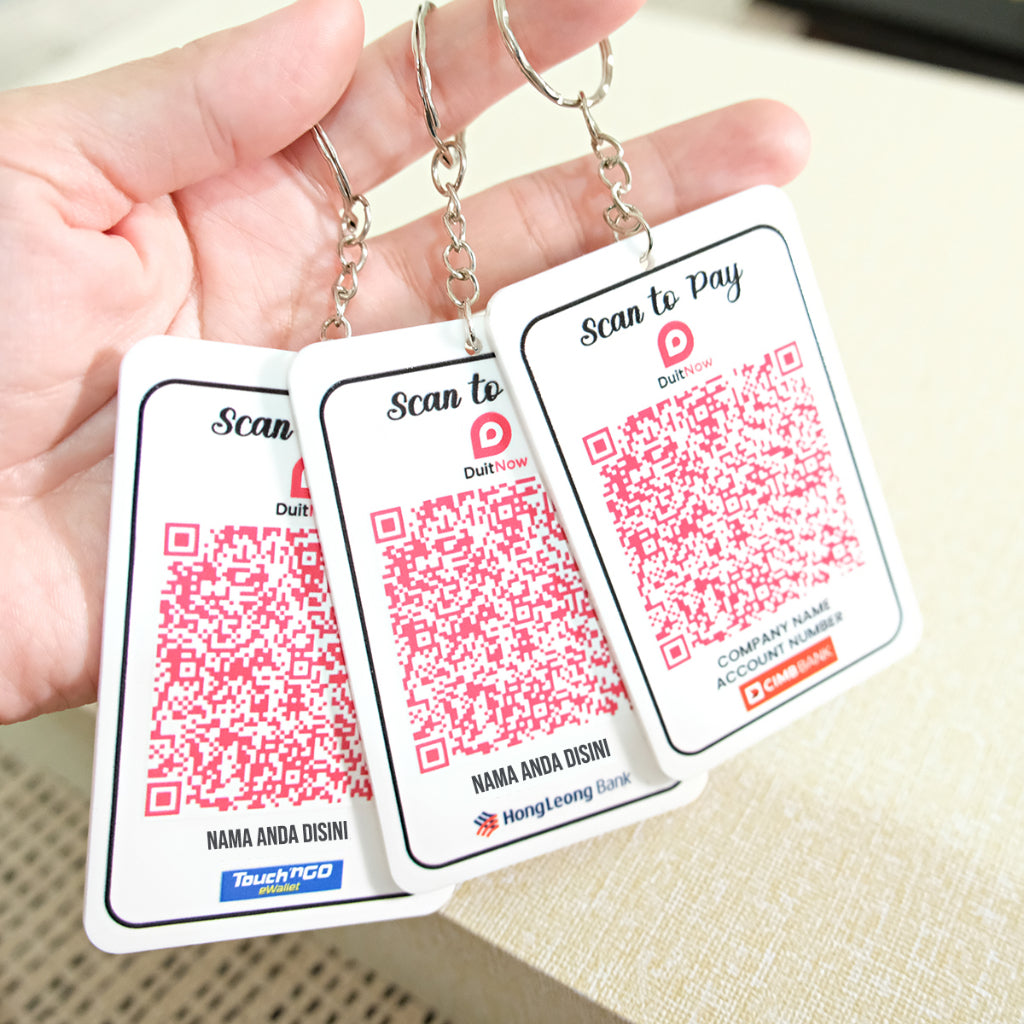 Three keychain cards with QR codes and branding held by a hand.