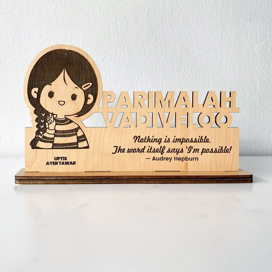A custom wooden table stand signage with an engraved portrait and text, displayed on a desk.