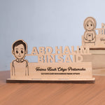Wooden plaque with a cartoon character and engraved text on a wooden stand.
