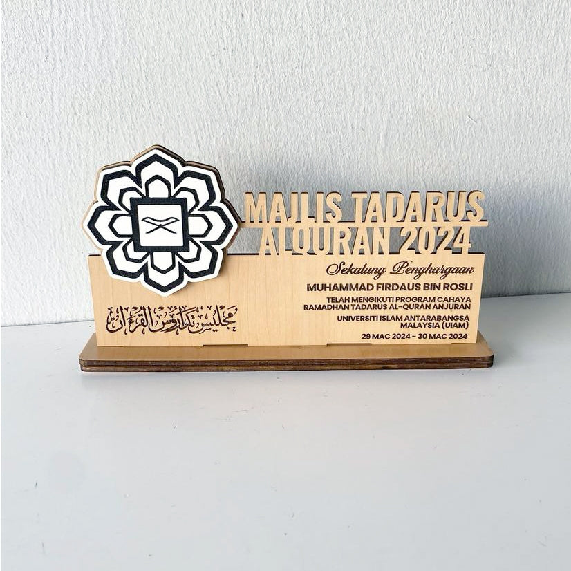 A custom wooden table stand signage with an engraved portrait and text, displayed on a desk.