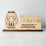 A custom wooden table stand signage with an engraved portrait and text, displayed on a desk.